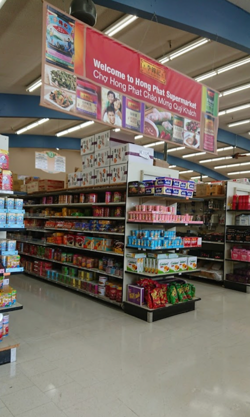 Interior of Hong Phat Supermarket, featuring shelves stocked with various food products and a welcoming sign.